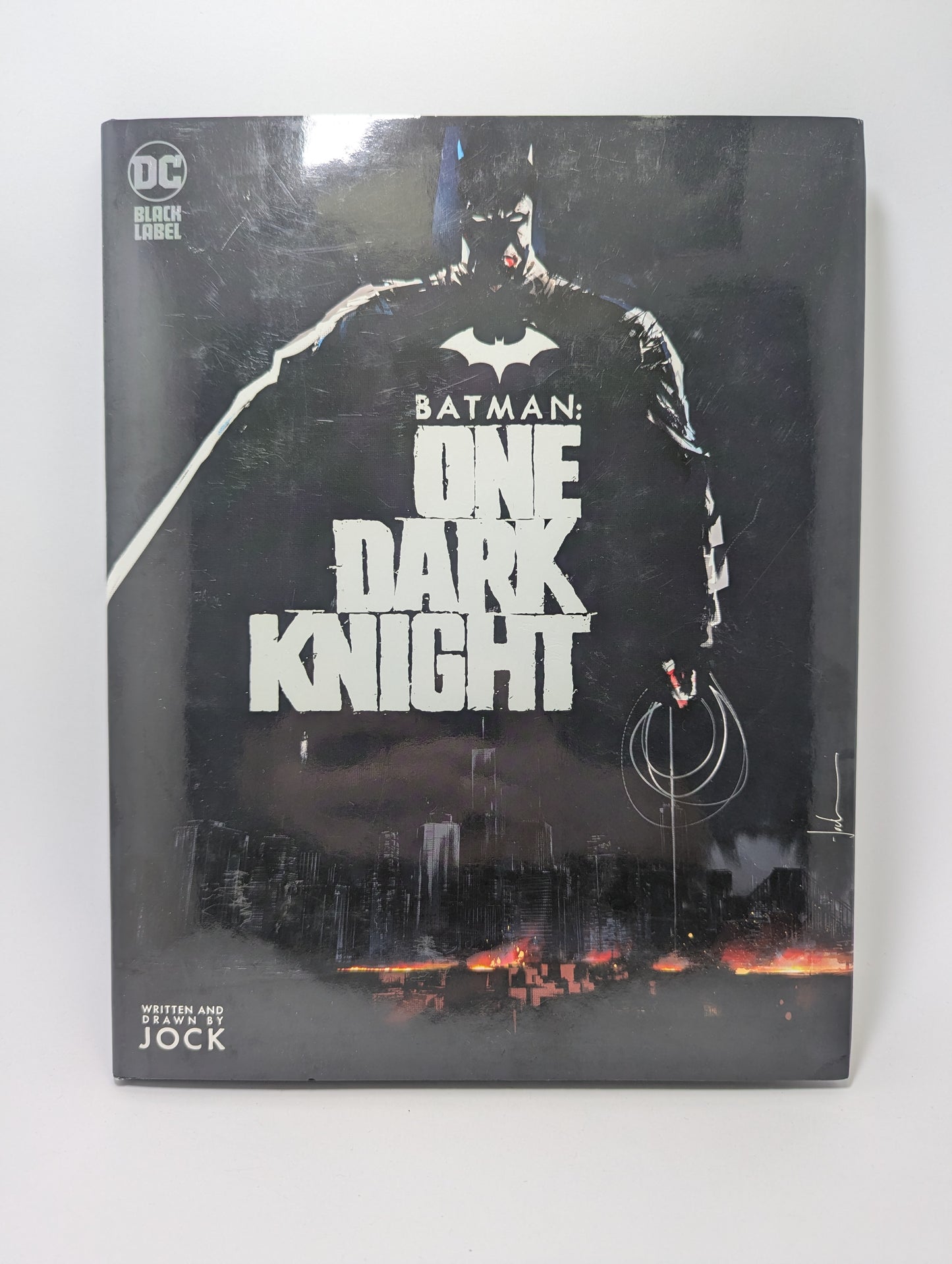 Grafinės novelės Batman: One Dark Knight viršelis su Tamsos riterio iliustracija tamsiose Gotamo gatvėse.