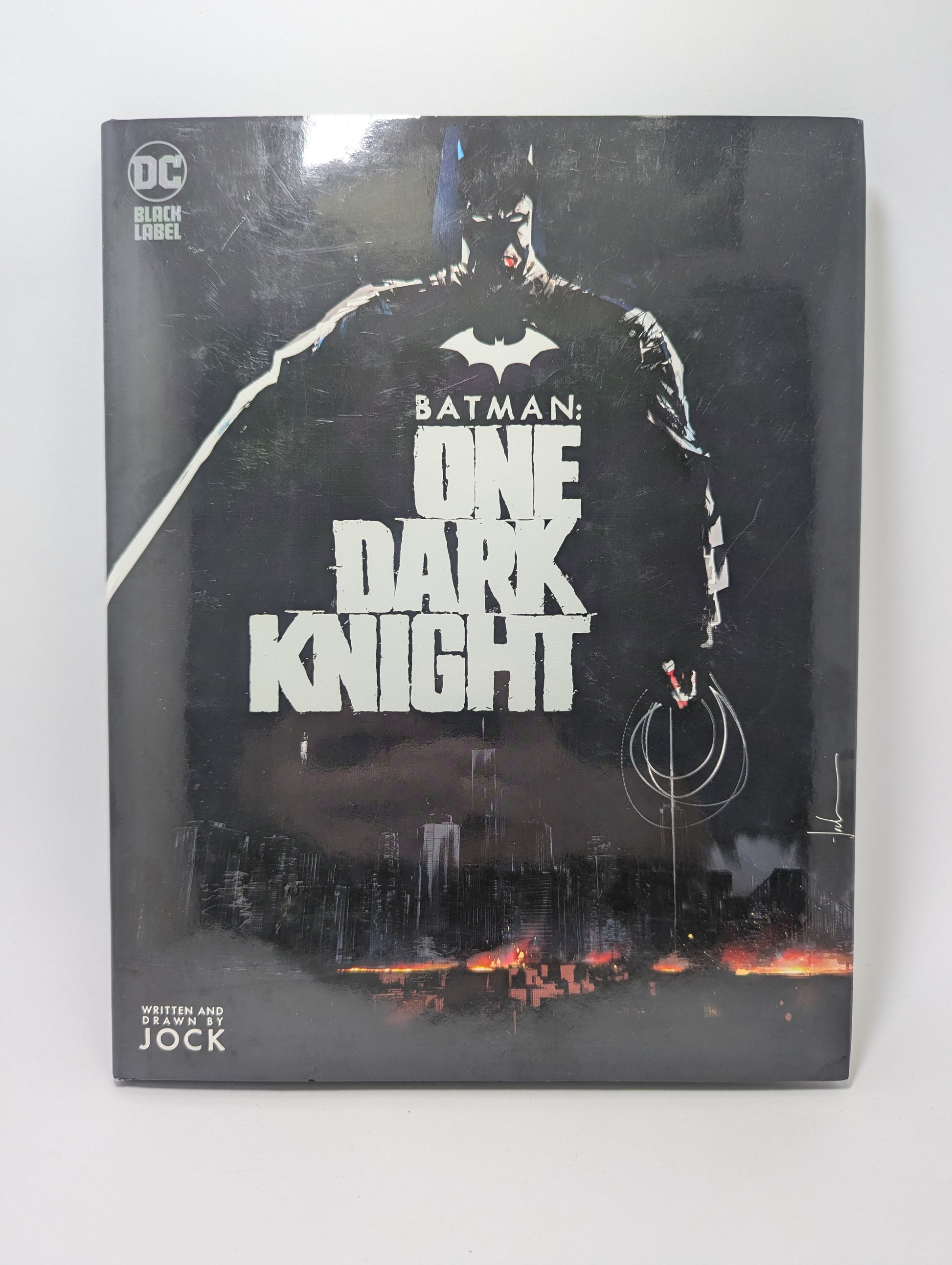 Grafinės novelės Batman: One Dark Knight viršelis su Tamsos riterio iliustracija tamsiose Gotamo gatvėse.